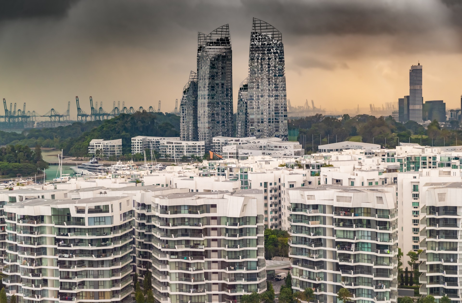 Top of real estate housing in down town of Singapore, few skyscrapers on background, storm sky at sunset